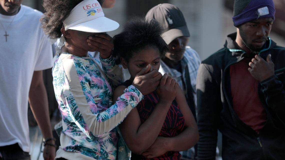 Bystanders look at the bodies of alleged gang members that were set on fire by a mob after they were stopped by police while traveling in a vehicle in the Canape Vert area of Port-au-Prince, Haiti, Monday, April 24, 2023.