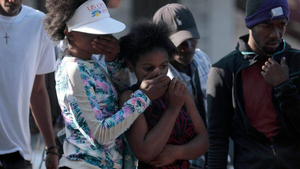 Bystanders look at the bodies of alleged gang members that were set on fire by a mob after they were stopped by police while traveling in a vehicle in the Canape Vert area of Port-au-Prince, Haiti, Monday, April 24, 2023.