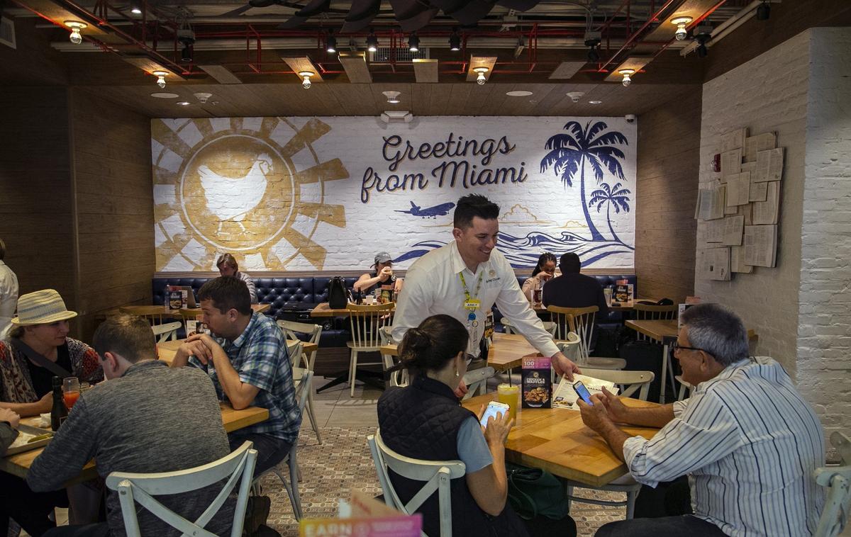 Un camarero atiende a clientes en el restaurante Spring Chicken del Aeropuerto Internacional de Miami, en una imagne del 4 de abril del 2019. El Condado Miami-Dade ha decidido eliminar la propina automática en los restaurantes del aeropuerto.