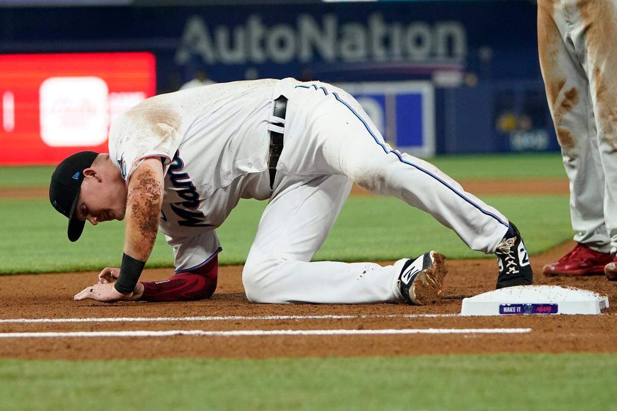 Miami Marlins first baseman Garrett Cooper gets up from the field after colliding with Philadelphia Phillies’ Nick Castellanos during the first inning of a baseball game, Saturday, April 16, 2022, in Miami. (AP Photo/Lynne Sladky)