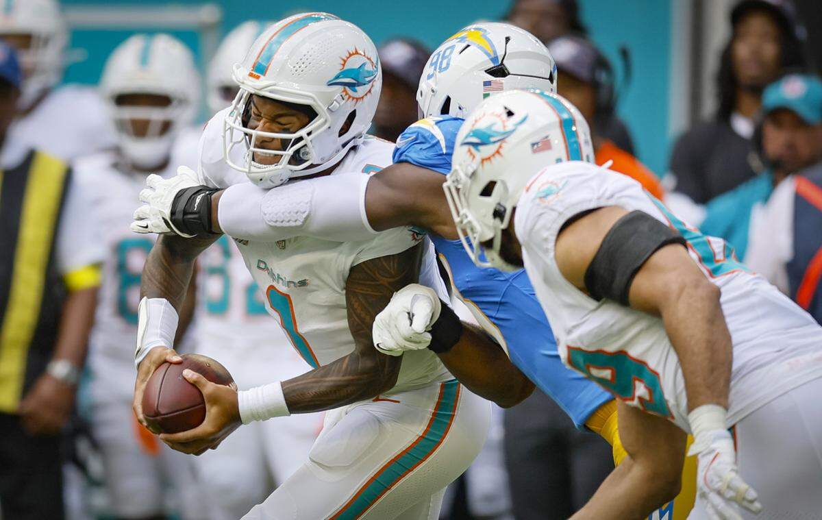 Miami Dolphins quarterback Tua Tagovailoa (1) is sacked by Los Angeles Chargers Odafe Oweh (98) in the first half during their NFL football game at Hard Rock Stadium in Miami Gardens, FL, on Sunday, October 12, 2025. 