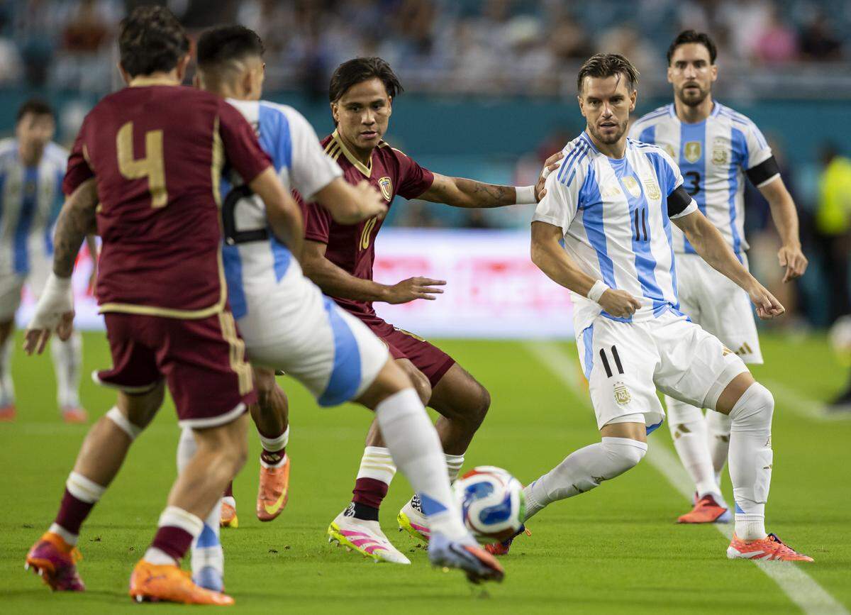Argentina midfielder Giovanni Lo Celso (11) passes the ball to forward Lautaro Martinez (22) as Venezuela midfielder Telasco Segovia (10) and defender Jon Aramburu (4) defend in the first half of their friendly soccer match at Hard Rock Stadium on Friday, Oct. 10, 2025, in Miami Gardens, Fla.