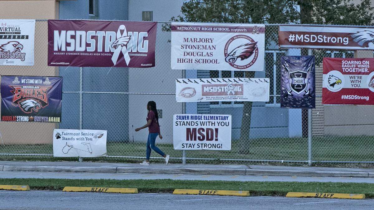 A student arrives for school Thursday, Feb. 14, 2019, during one year anniversary of the shooting deaths of 17 at Marjory Stoneman Douglas High School in Parkland, Fla. The building in background is where much of the shooting took place.