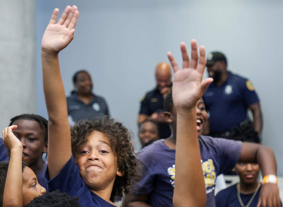 Ian Flores, 7, left, raises his hand in attempt to answering a question for a prize.