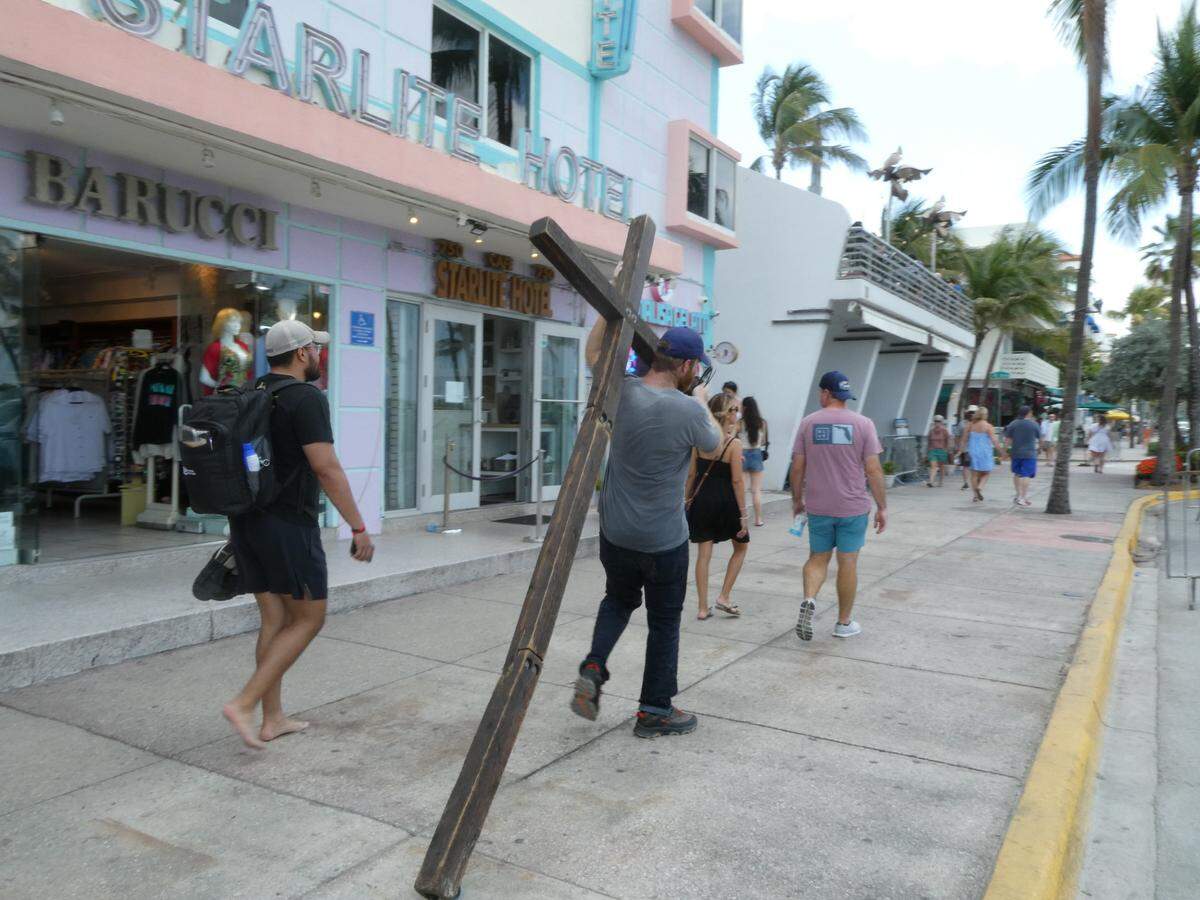 Wade Aaron, 35, walked along Ocean Drive, lugging a large, wooden cross over his shoulder, while visiting Miami Beach during spring break on Sunday, March 10, 2024.