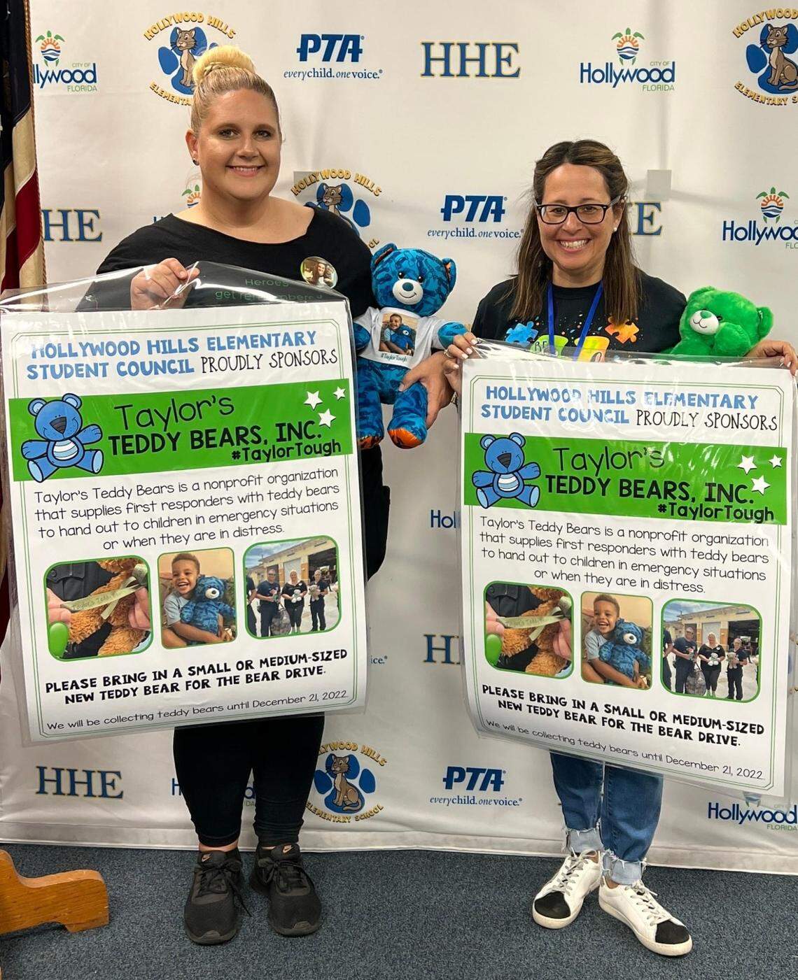 Megan Bishop, left, and Laurie Kraus, right, hold up posters for the bear drive at Hollywood Hills Elementary School. Bishop’s son Taylor Bishop died last year when a plane crashed into an SUV in Pembroke Pines.