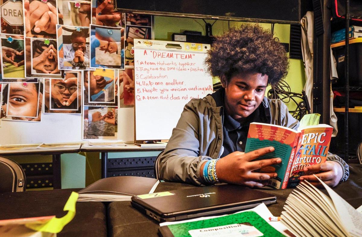 Khristian Benn, 13, reads a book while studying in class at Urgent Academy Middle School.