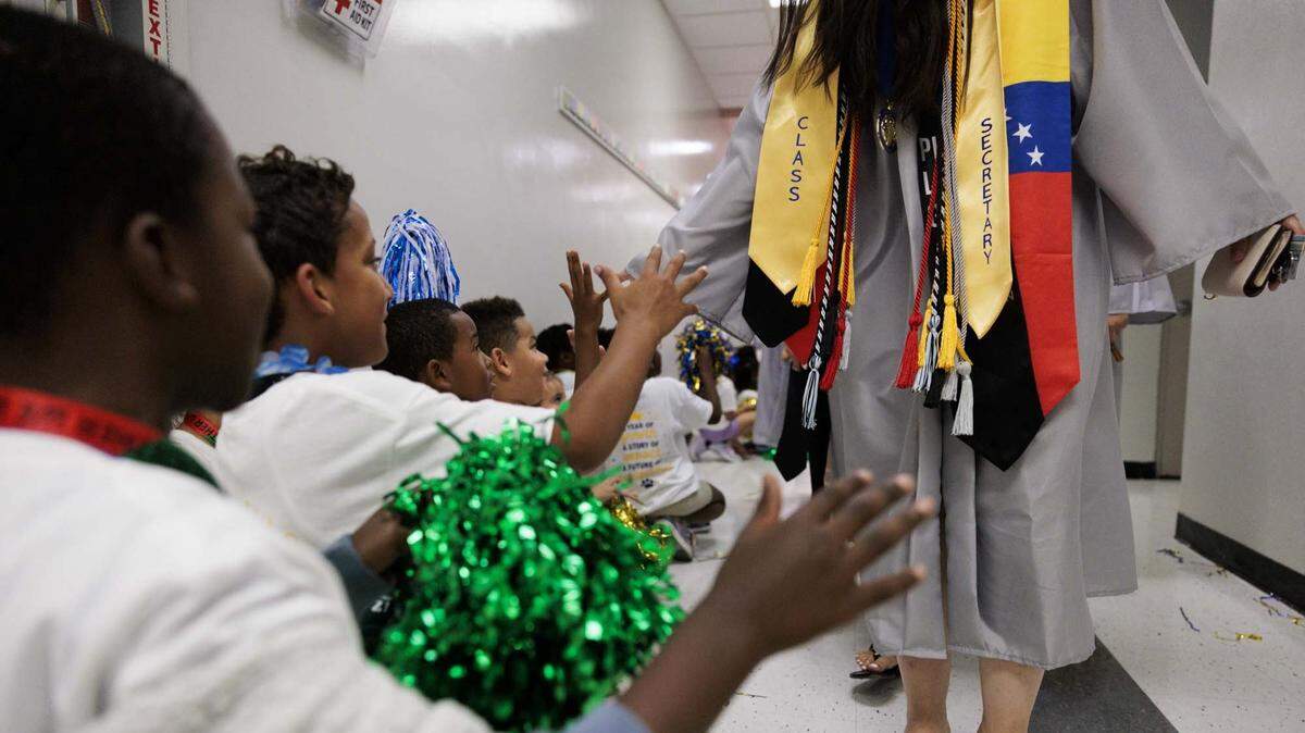 A student from Panther Run Elementary high fives a high school graduate, who also attended the school, as the alumni walk the halls on Monday, June 1, 2026, in Pembroke Pines, Fla. The school invited graduating alumni, from as far as Illinois, to come and walk through their former elementary school to celebrate their high school graduation before it closes. 