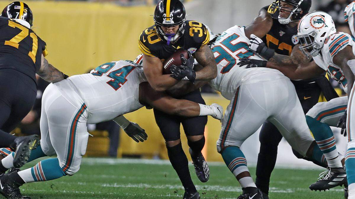 Pittsburgh Steelers running back James Conner (30) is tackled by Miami Dolphins defensive tackle Christian Wilkins (94) and defensive tackle John Jenkins (95) during the first half of a football game in Pittsburgh, Monday, Oct. 28, 2019. (AP Photo/Keith Srakocic)
