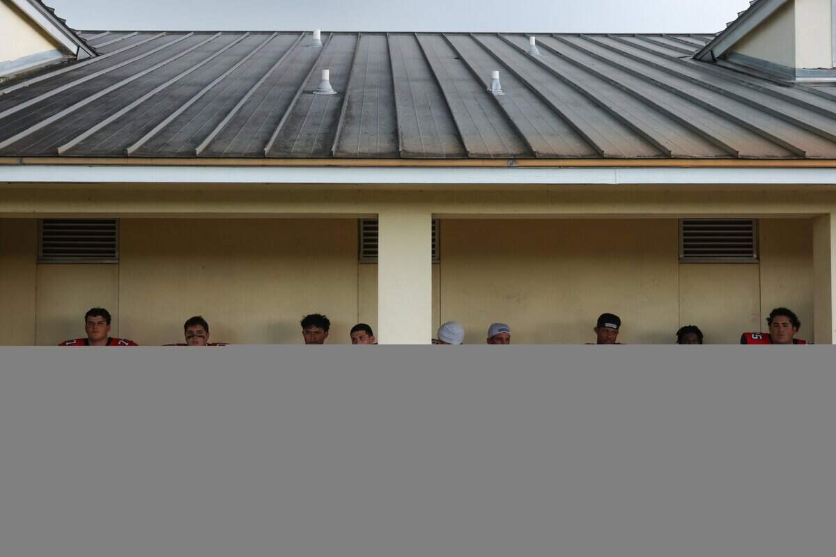 Columbus Explorers football players wait during a lighting delay before a high school football game against the Southridge Spartans at Tropical Park Stadium in Miami, Florida, Thursday, August 21, 2025.