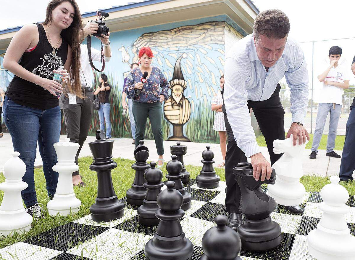 From left,  Gabriela Perez and Hialeah Mayor Carlos Hernandez play a giant game of chess at Hialeah’s new Domino Park on Thursday, July  16, 2018.