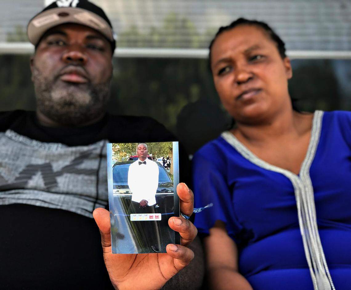 Penel Jean, left, and Mirline Jean, hold a photo of their son Lens Desir, who was one of the three young soccer players killed while waiting for the team bus early Saturday morning for soccer match in Weston.
