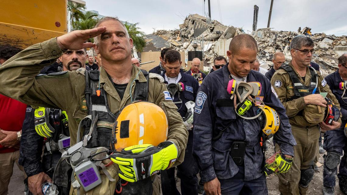 Surfside, Florida, July 7, 2021 - A Member of the Israeli search and rescue team salutes in front of the rubble that once was Champlain Towers South during a prayer ceremony.