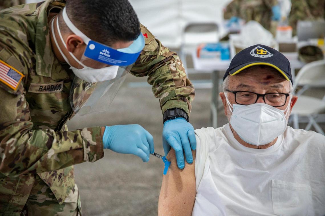 Issac Chanavich, 82, is injected with a COVID-19 vaccine by a U.S. Military medic during opening day of the FEMA vaccination site on Miami Dade College’s North Campus on Wednesday, March 3, 2021.