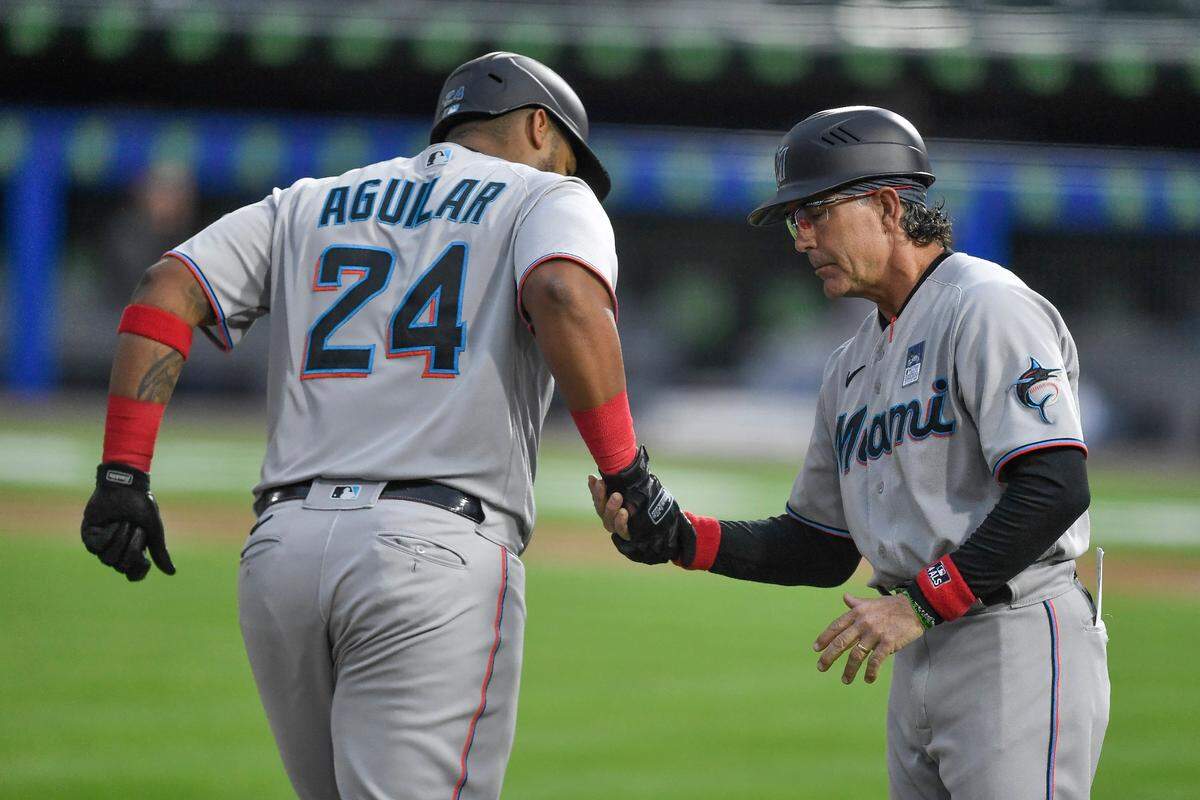 Miami Marlins’ Jesus Aguilar (24) is congratulated by third base coach Trey Hillman after hitting a solo home run against the Toronto Blue Jays during the third inning of a baseball game in Buffalo, N.Y., Wednesday, June 2, 2021. (AP Photo/Adrian Kraus)