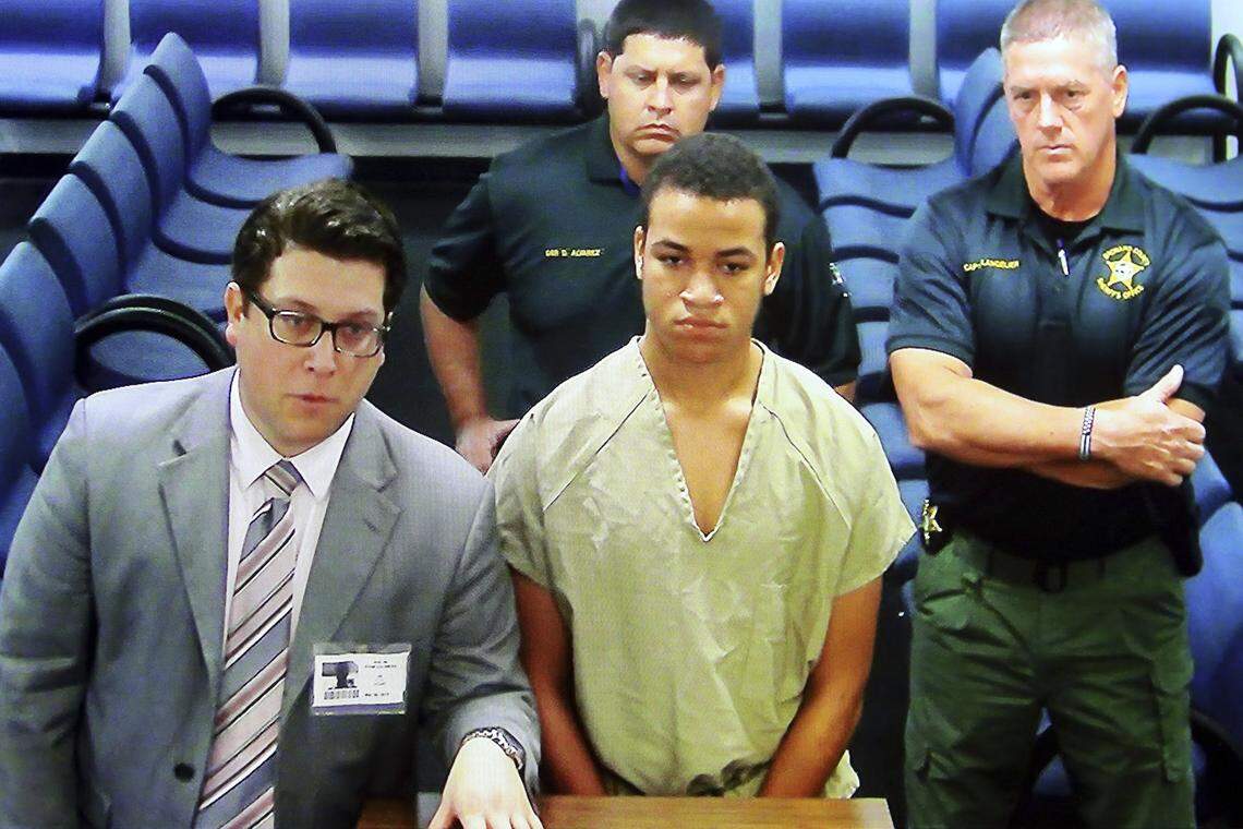 Zachary Cruz, center, the brother of the Florida school shooter, makes his first appearance, via video monitor, after his arrest weeks after the massacre for trespassing on the grounds of Marjory Stoneman Douglas High School.