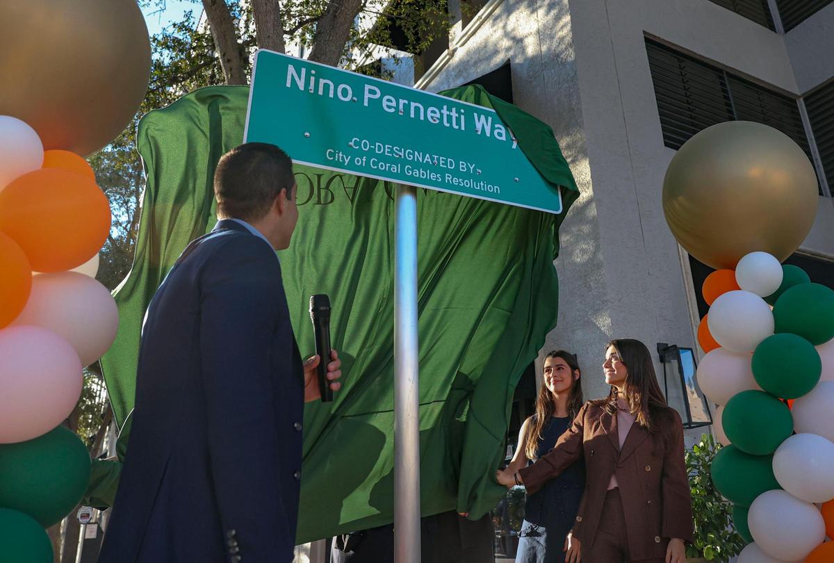 Mayor Vince Lago, left, and the daughters of the late Nino Pernetti, Katerina, center, and Tatiana unveil the sign renaming part of Aragon Ave. “Nino Pernetti Way” in honor of their father.