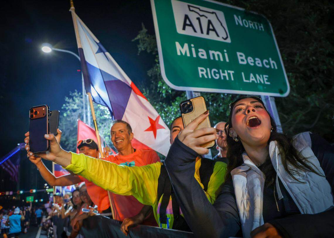 Marathon attendees cheer on runners on the racecourse, waving flags and signs and offering words of encouragement as large groups make their way towards the causeway during the Life Time Miami Marathon & Half on Sunday, January 25, 2026, in Miami, Florida.