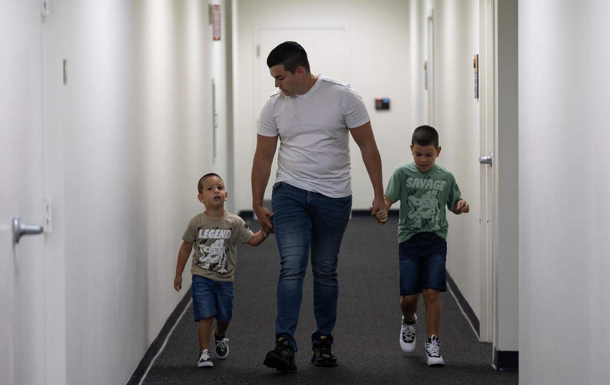 Brayan Soto, de 26 años, centro, y sus hijos, Jeison Soto, de 3 años, izquierda, y Michele Soto, de 7, caminan por un pasillo en la Corte de Inmigración en el centro de Miami, Florida.