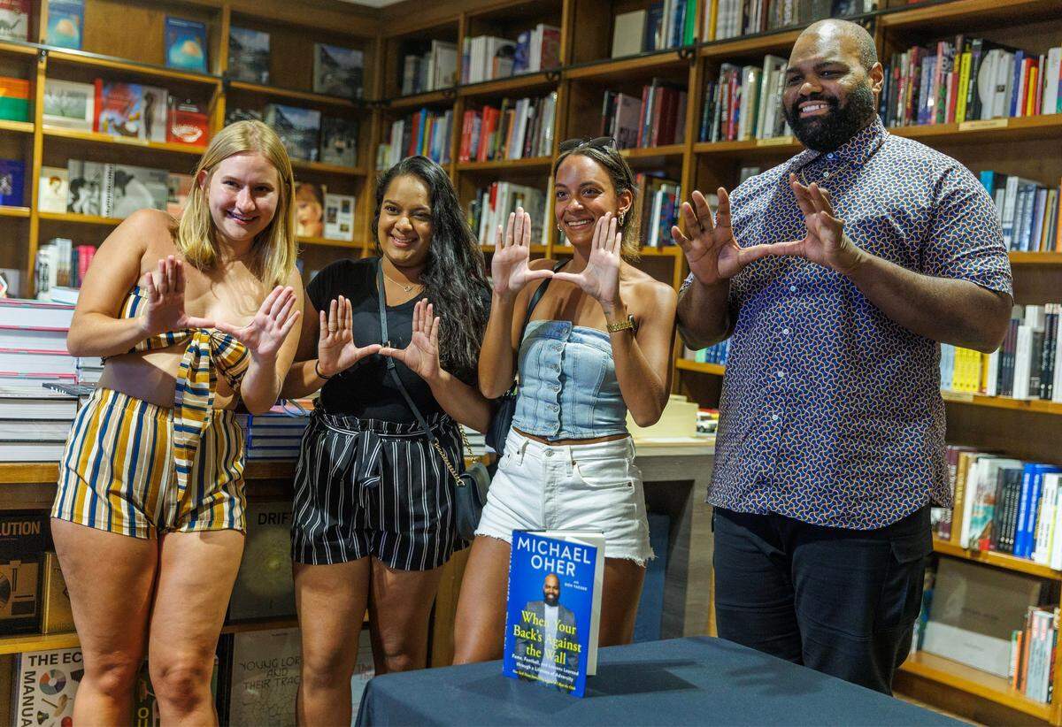 El autor Michael Oher hace la "U" con las estudiantes de derecho de la UM (de izquierda a derecha) Megan Nubauer, Sharmila Singh y Megan Williams, después de autografiar su libro titulado 'When Your Back's Against the Wall: Fame, Football, and Lessons Learned through a Lifetime of Adversity' en Books &amp; Books, en Coral Gables, el miércoles 23 de agosto de 2023.