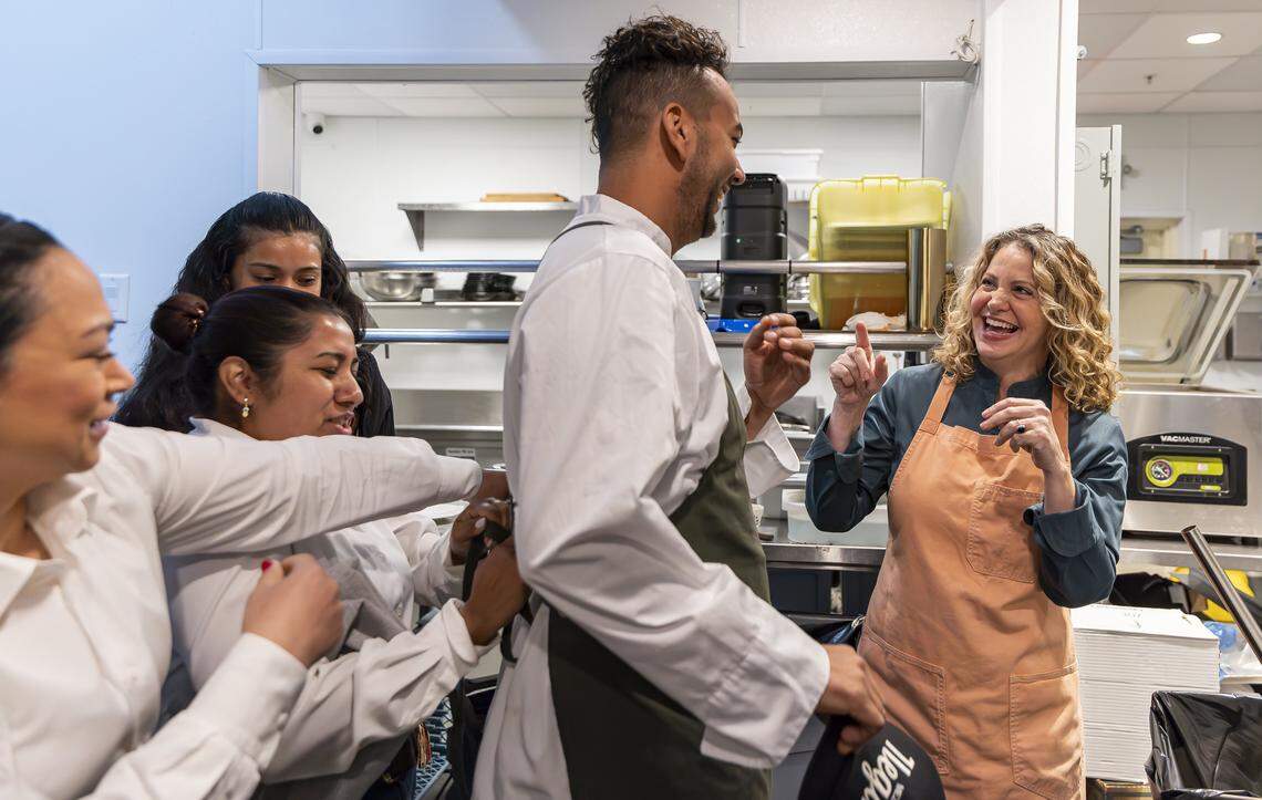 Chef Michelle Bernstein, right, reacts while speaking with Chef Isaiah Toledo, 30, as staff help him put on his apron at their restaurant, Sra. Martinez, on Thursday, Jan. 29, 2026, in Coral Gables, Fla. Bernstein is being honored this year at the South Beach Wine & Food Festival.