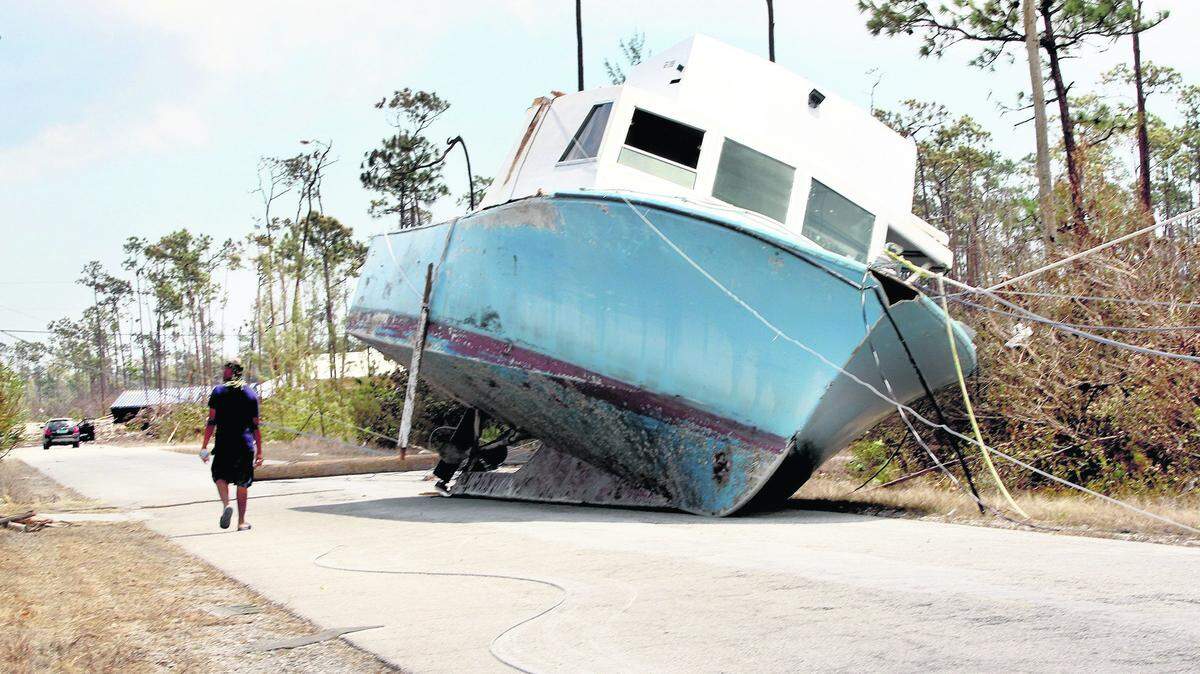 Resident Shawn Sturup walks by a boat stranded in the middle of the street by storm surge during Hurricane Dorian in the Fortune Bay neighborhood of Grand Bahama, on Friday, September 06, 2019.