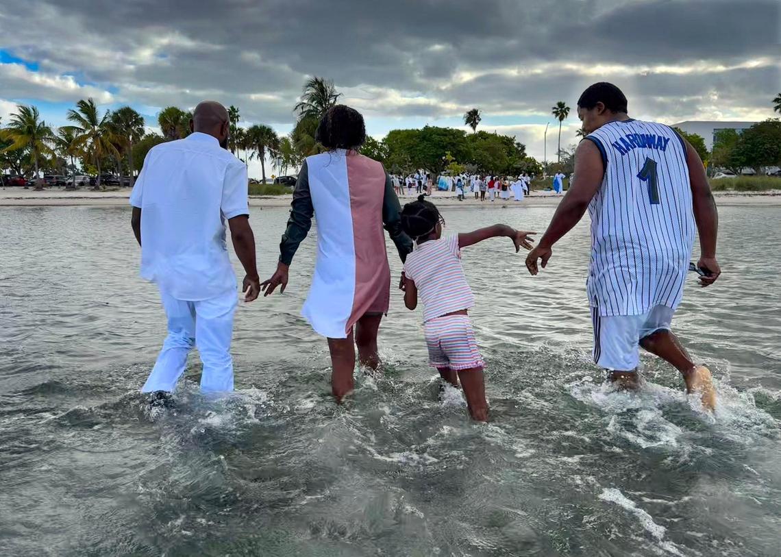 Associate pastor Jarrett Durden, 43, left, escorts members of the Quinn family - Ernisha Quinn, 34, her daughter, Tehgan, 6, and her brother, Earnest Quinn, 29, back to shore after they all were baptized under a cloudy sky. Jesus Christ True Church held baptisms on Easter Sunday to symbolize rebirth, which coincides with the story of Jesus’ resurrection.