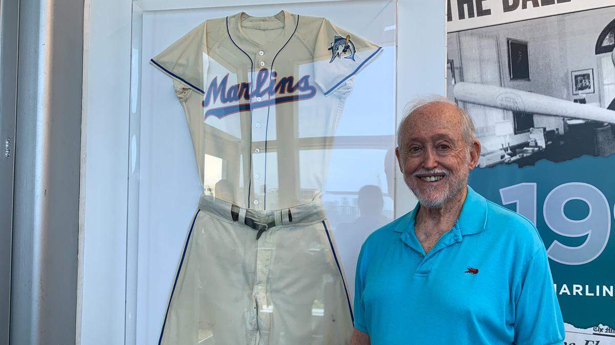 Tim Anagnost, the original batboy for the Triple A Miami Marlins, poses next to his uniform from the 1956 season inside the Marlins Museum on Sunday, June 25, 2023, at loanDepot park.