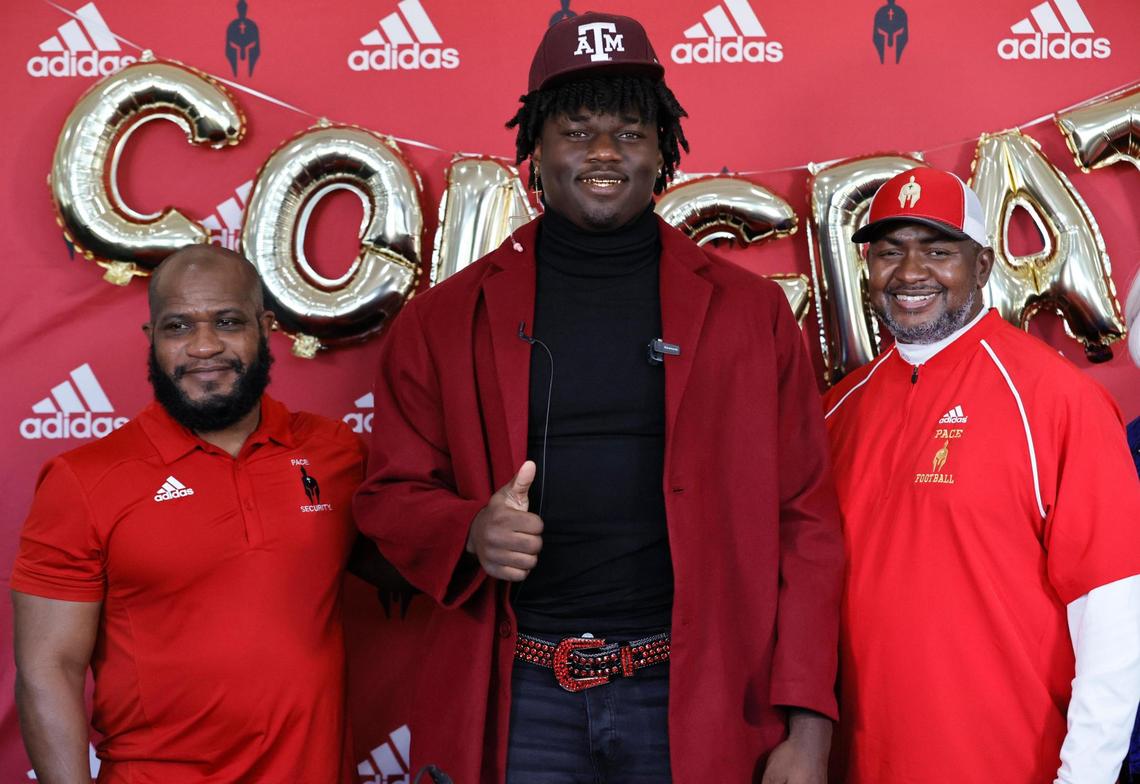 Monsignor Edward Pace coaches Anthony Walker and Corvin Lamb pose with Pace defensive end Shemar Stewart after choosing to sign with Texas A&M University football during National Signing Day at Monsignor Edward Pace High School in Miami Gardens, Florida, on Wednesday, February 2, 2022.