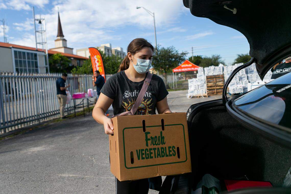 Sophia Brito-Travieso, 12, loads up a vehicle during a drive-thru food distribution event in Hialeah on Saturday, December 5, 2020.