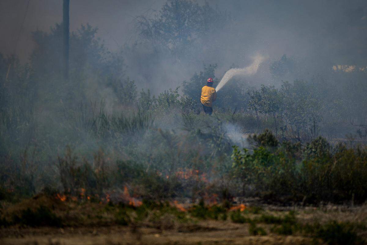 A firefighter fights a grass fire in Kamloops, British Columbia, on Monday, June 5, 2023.