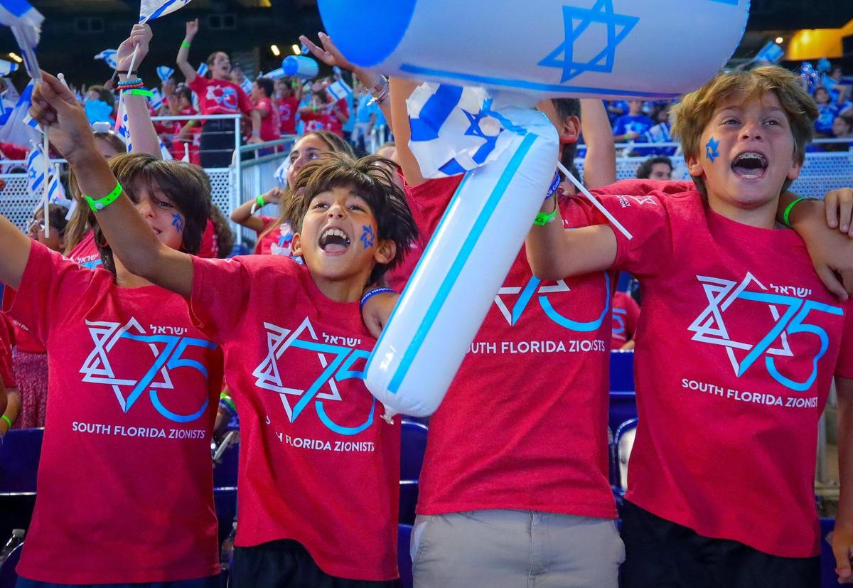 Ben Gamla Charter School Hollywood students Ori Kanfi, 11, left, Leroy Lev, 11, Mike Breslauer, 12, center, and David Leibovich, 11, right, sing as they wave flags in celebration of the statehood anniversary of Israel at the Marlins baseball stadium in Miami.
