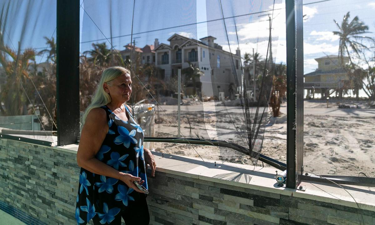 Heidi Christianson, 66, a retired landlord, stands by her pool screen that was damaged by Hurricane Ian inside her home on Tuesday, Oct. 18, 2022, in Bonita Beach, Florida.