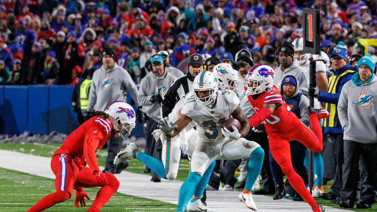 Miami Dolphins running back Raheem Mostert (31) runs the football against Buffalo Bills safety Damar Hamlin (3) and Bills cornerback Dane Jackson (30) during fourth quarter of an NFL football game at Highmark Stadium on Saturday, December 17, 2022 in Orchard Park, New York.