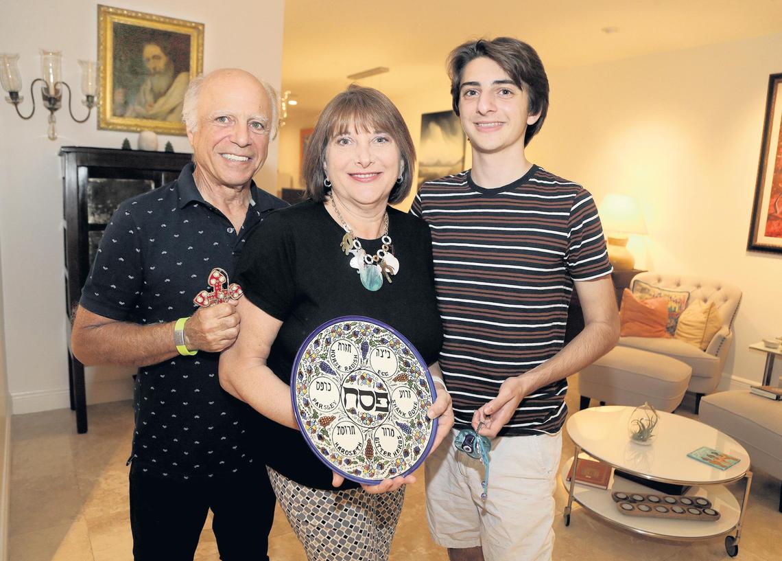 Karen Davis, who is Jewish, and her husband Nick Athanassiadis, who is Greek Orthodox, with their son Michael. She is holding a Seder plate for Passover and he is holding a cross for Easter. The family embraces both religions.