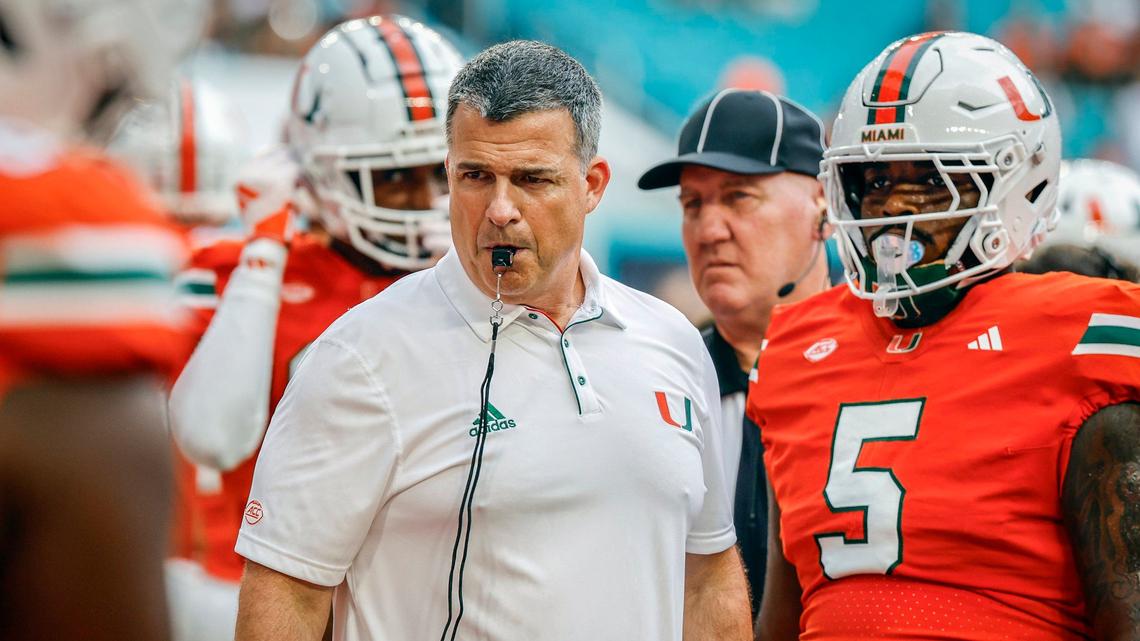 Miami Hurricanes head coach Mario Cristobal works with players during warmups before the start of the Miami Hurricanes NCAA football game against the Ball State Cardinals at Hard Rock Stadium in Miami Gardens, Florida on Saturday, September 14, 2024.