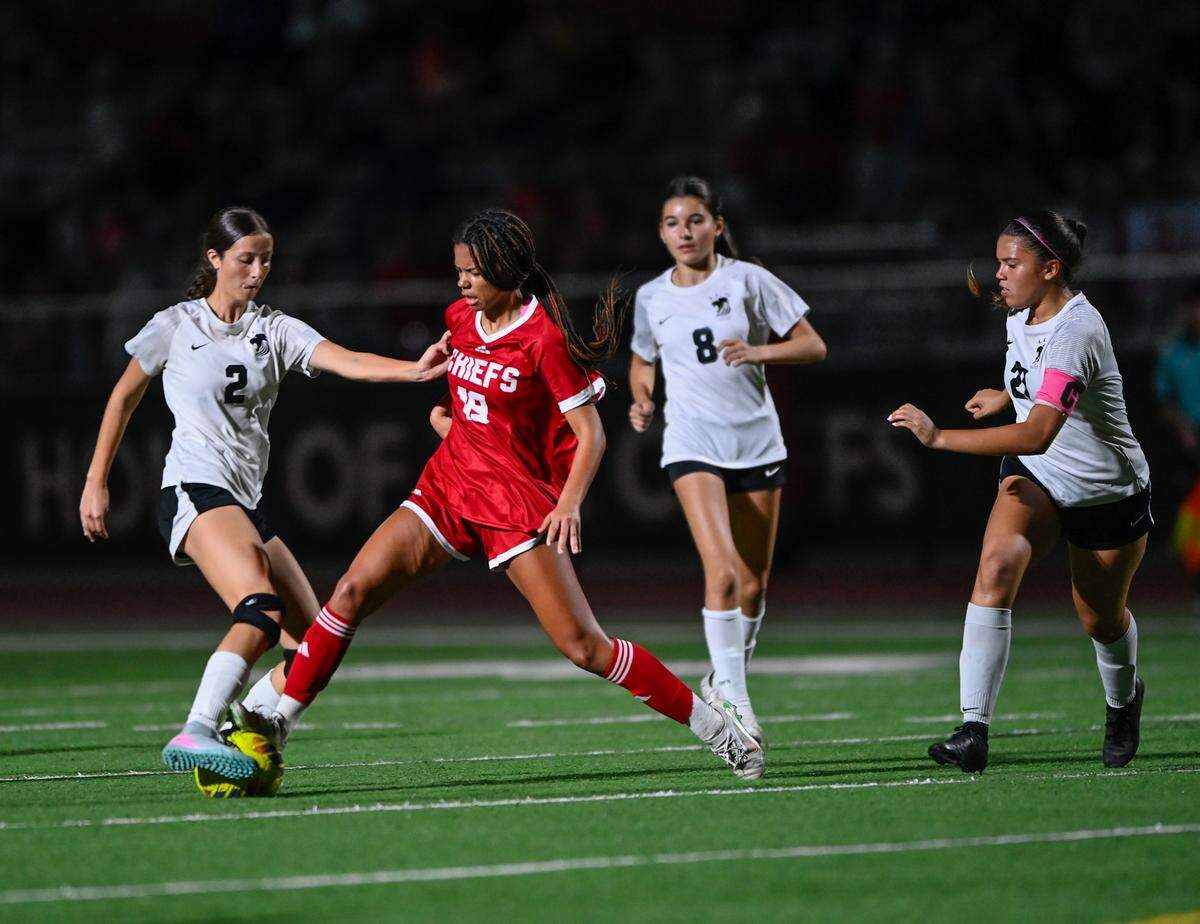 Cardinal Gibbons’ Reagan Hood (red jersey) battles Isabella Studenski (left) for the ball during Friday’s Region 4-3A final at Gibbons High in Fort Lauderdale.