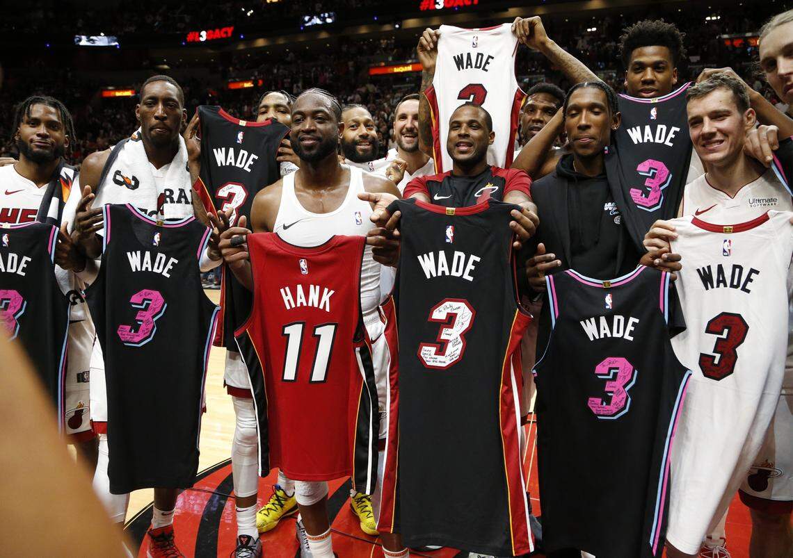 Miami Heat guard Dwyane Wade (3) holds a jersey (11) with the name of his agent, Henry Thomas, who died in 2018, with teammates at the end of the game against the Philadelphia 76ers at the AmericanAirlines Arena in Miami on Tuesday, April 9, 2019.