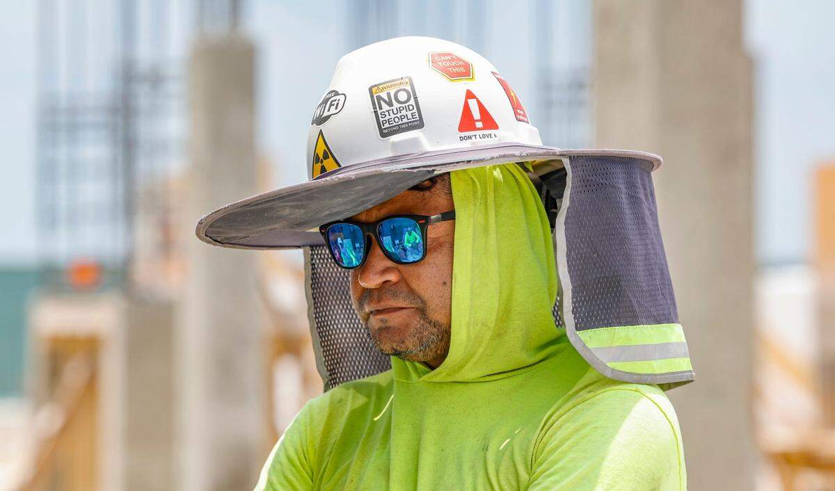 Laborer Elvin Murillo wears protective gear to battle the sun at a residential construction site on Key Biscayne, Florida on Friday, May 17, 2024.