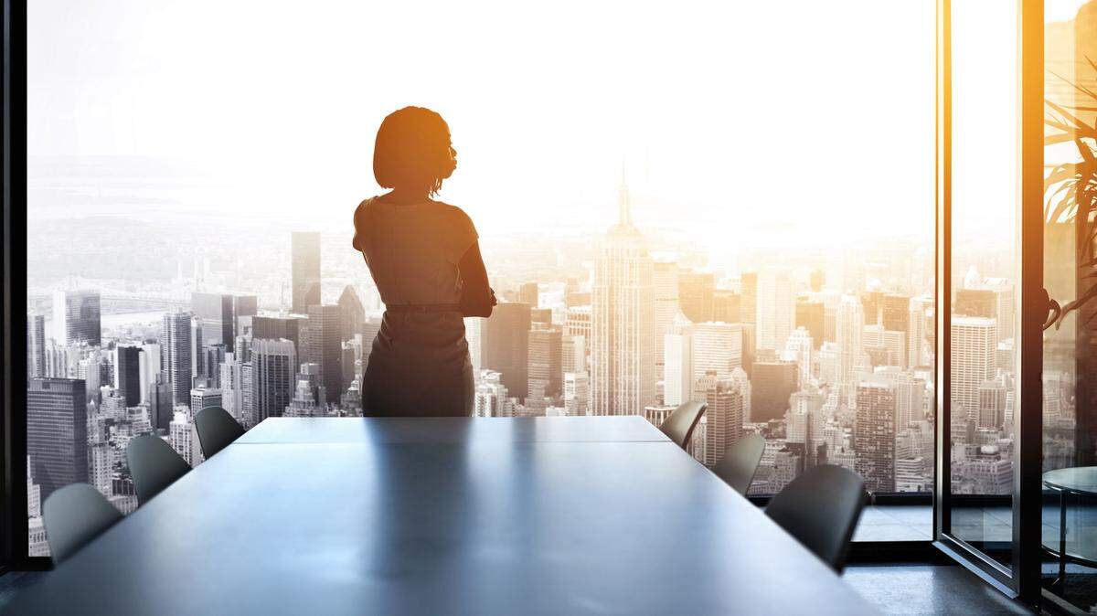Rearview shot of a young businesswoman looking out from a large window in the office