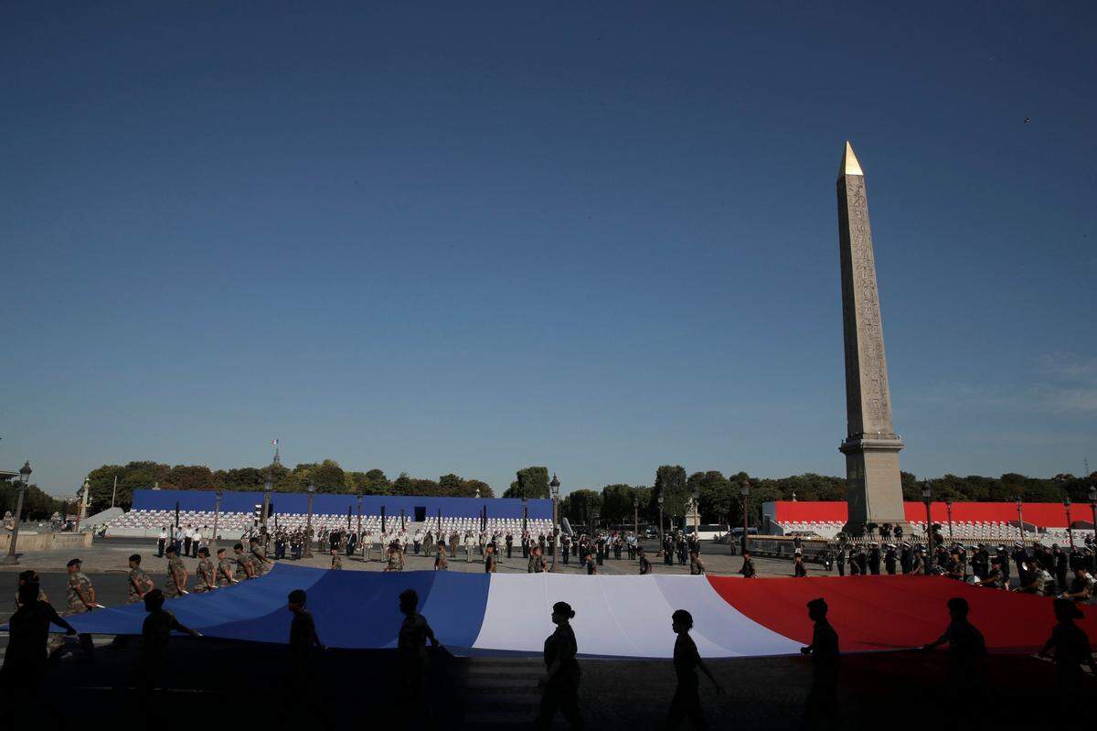 Soldiers hold a French flag during a rehearsal for the Bastille Day parade on the Concorde square in Paris Monday, July 13, 2020. Bastille Day is the French national holiday that commemorates the Storming of the Bastille on July 14, 1789, a turning point of the French Revolution.