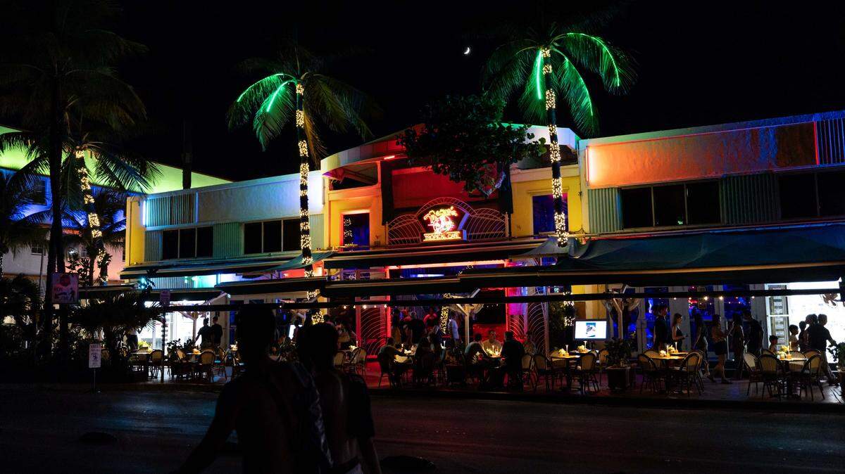 People walk down Ocean drive past Mango's Tropical Cafe on Monday, July 28, 2025, in Miami Beach, Fla.