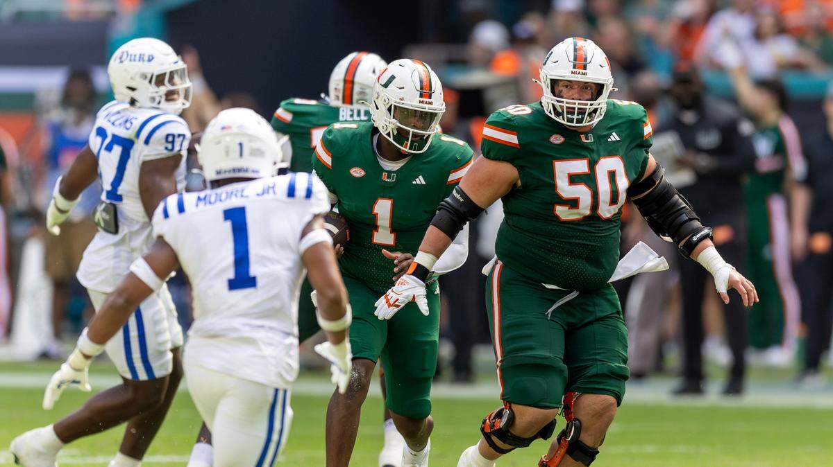 Miami Hurricanes quarterback Cam Ward (1) scrambles for yardage as Hurricanes center Zach Carpenter (50) blocks during the first half of an ACC football game against the Duke Blue Devils at Hard Rock Stadium on Saturday, Nov. 2, 2024, in Miami Gardens, Fla.