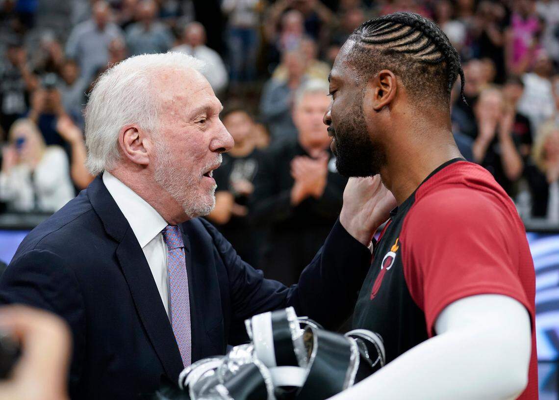 Miami Heat guard Dwyane Wade, right, accepts a gift from San Antonio Spurs coach Gregg Popovich before an NBA basketball game Wednesday, March 20, 2019, in San Antonio.