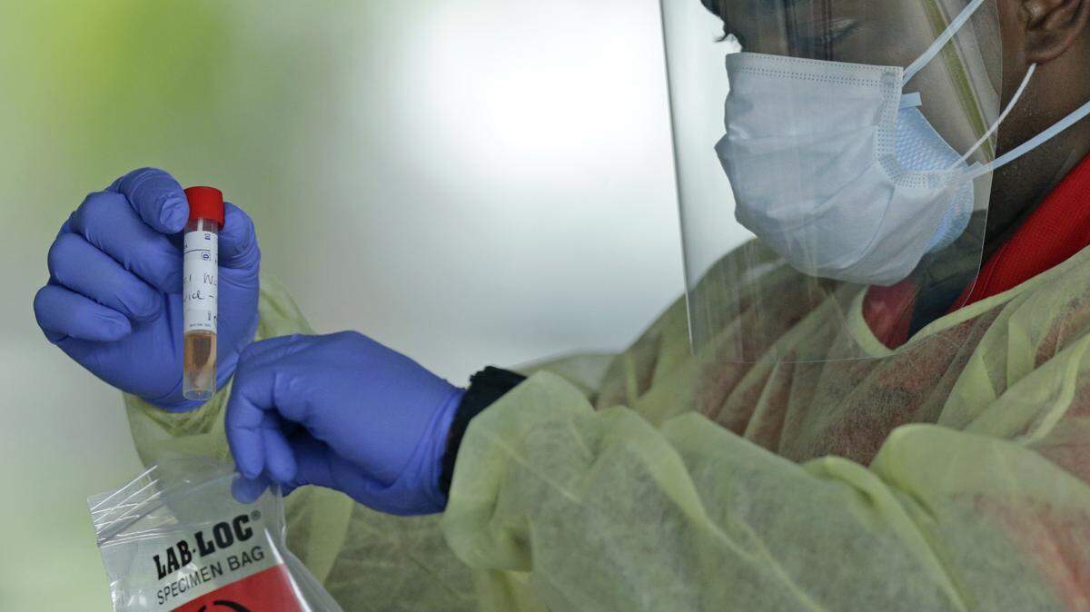 An American Medical Response health worker holds a test swab at the COVID-19 drive-thru testing center at Holiday Park, 1150 G. Harold Martin Drive in Fort Lauderdale, last April.