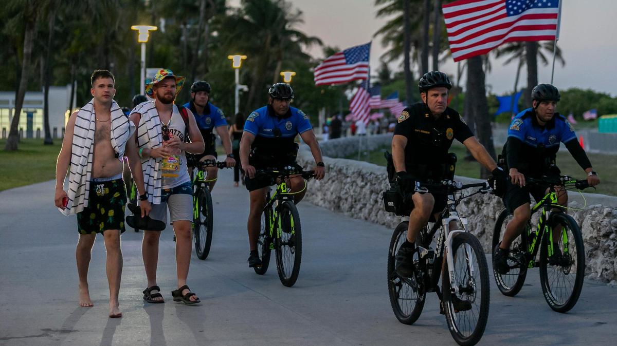 Los bañistas recorren Lummus Park mientras los policías patrullan cerca de Miami Beach, Florida, durante el inicio del fin de semana del Memorial Day el viernes 28 de mayo de 2021.