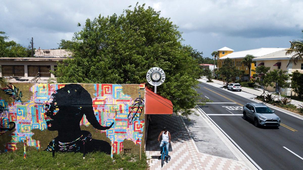 A man makes his way down Sistrunk Boulevard near Cone Plaza on Tuesday, July 2, 2024, in Fort Lauderdale, Florida. The building, which belonged to the late William J. Cone, is scheduled for demolition after the building caught fire.