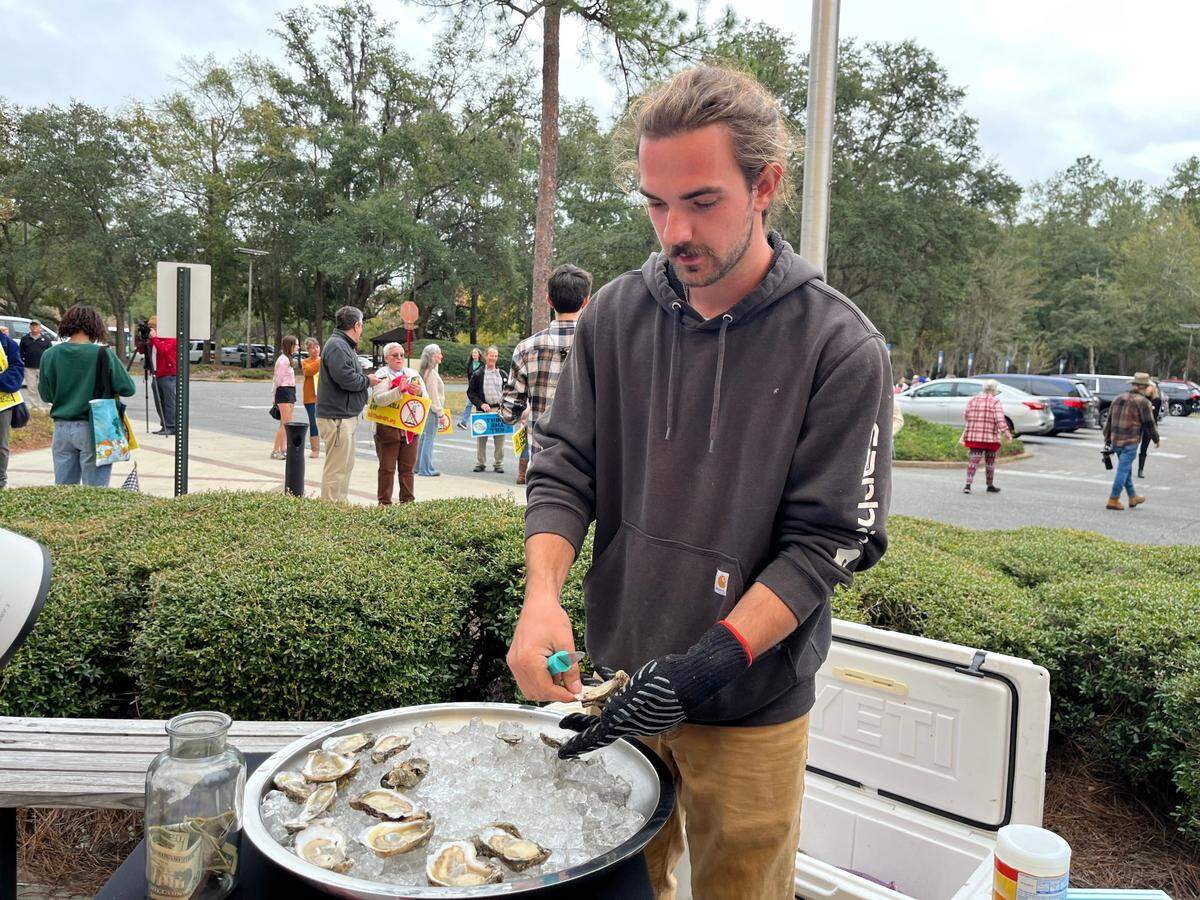 Grayson Hall, whose brother owns an Apalachicola Bay oyster farm, shucks oysters outside the Florida Department of Environmental Protection’s headquarters in Tallahassee on Monday, Dec. 9, 2024.