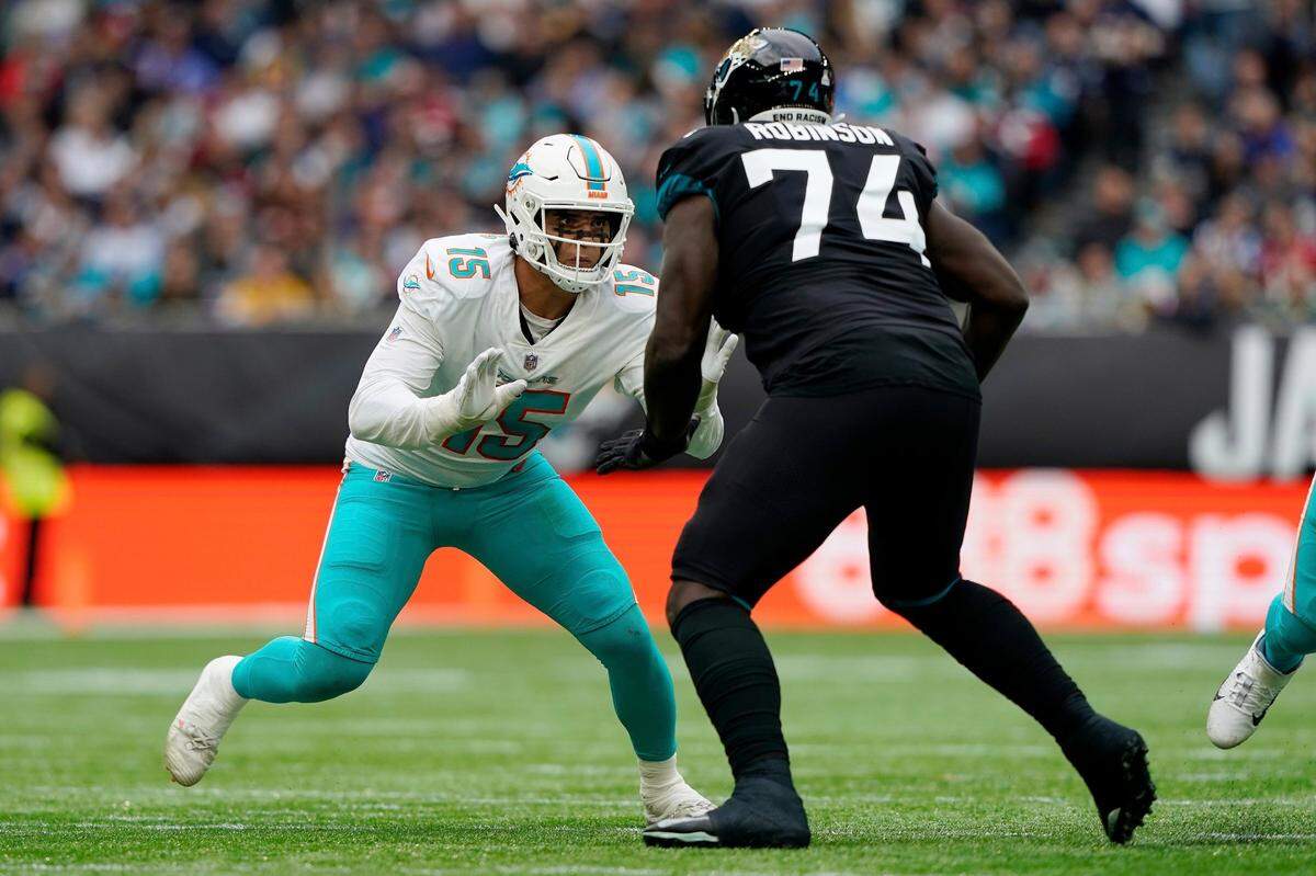Miami Dolphins outside linebacker Jaelan Phillips (15) moves in to blok Jacksonville Jaguars offensive tackle Cam Robinson (74) during an NFL football game at Tottenham Hotspur Stadium in London, Sunday, Oct. 17, 2021. The Jacksonville Jaguars defeated the Miami Dolphins 23-20. (AP Photo/Steve Luciano)