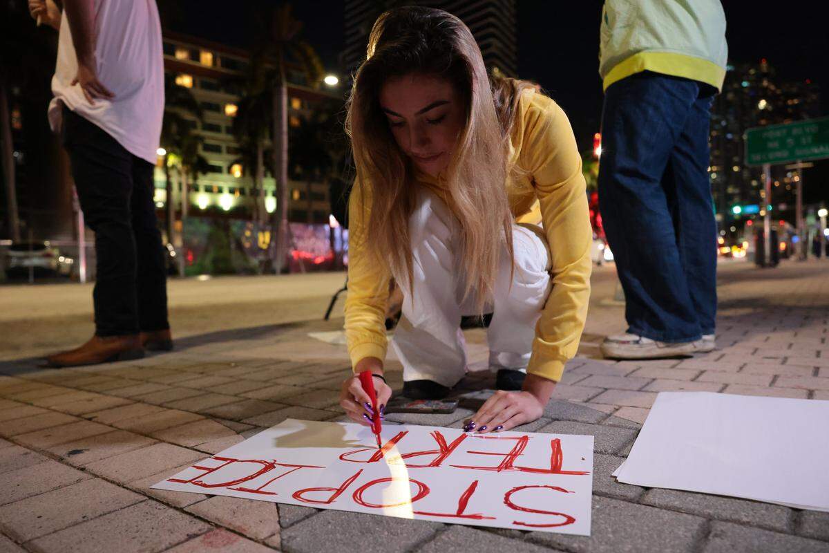 Peach Martine, 23, makes a sign while protesting against ICE at the Torch of Friendship monument at 401 Biscayne Blvd., in downtown on Wednesday, Jan. 7, 2026, in Miami.